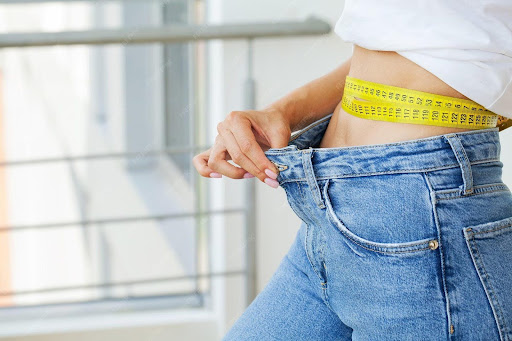 Woman in oversized jeans after weight loss.